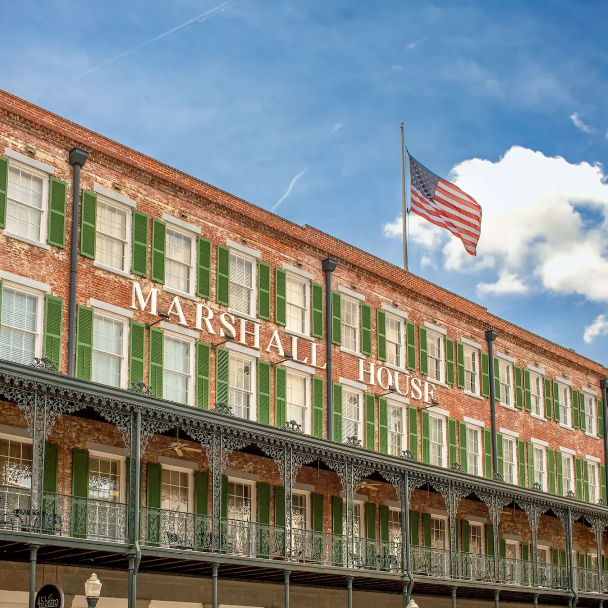 the facade of the Marshall House in Savannah Georgia, with a large American flag flying above