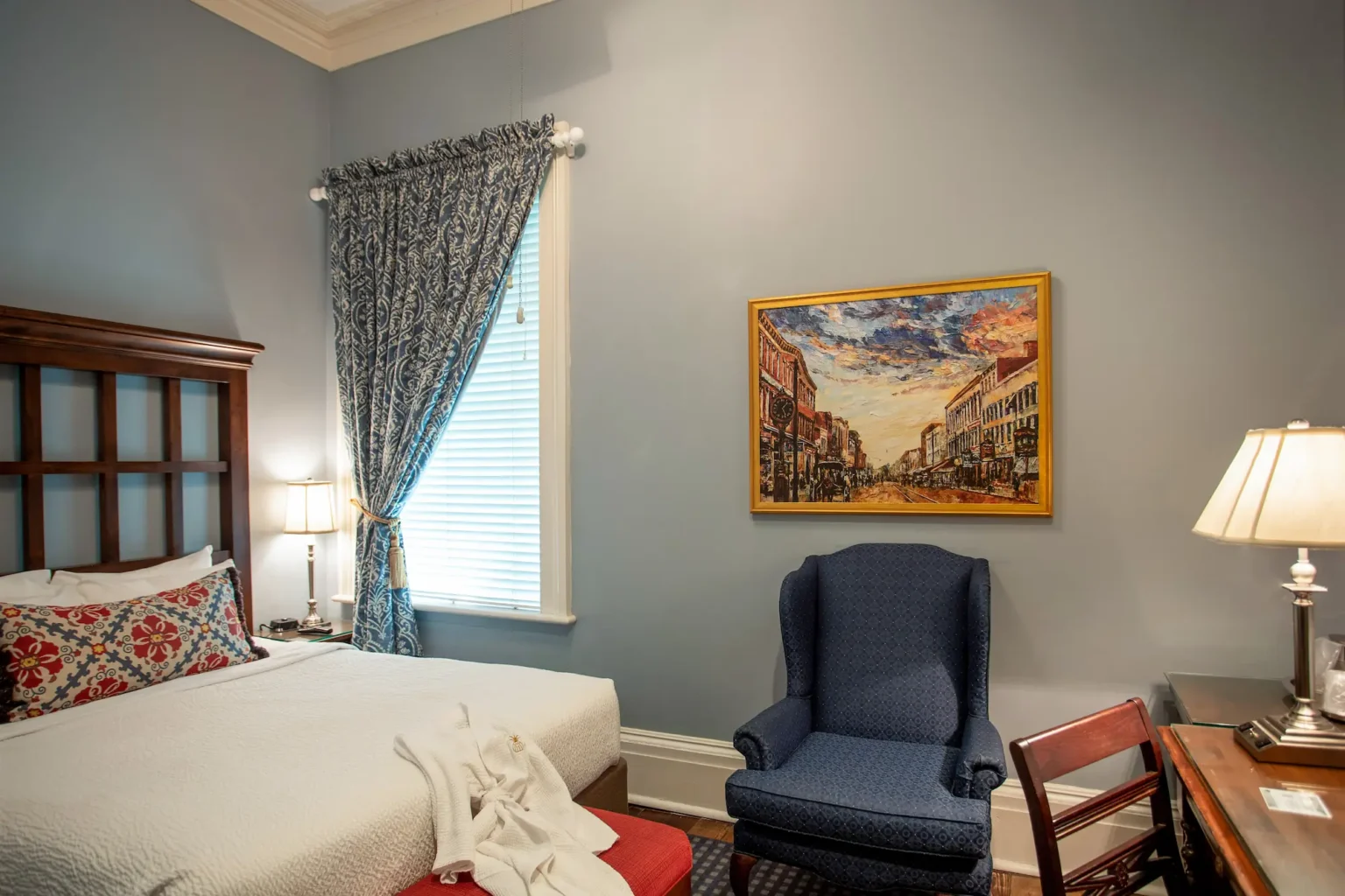 bed, chair, and art in the petite queen room at the Marshall House hotel