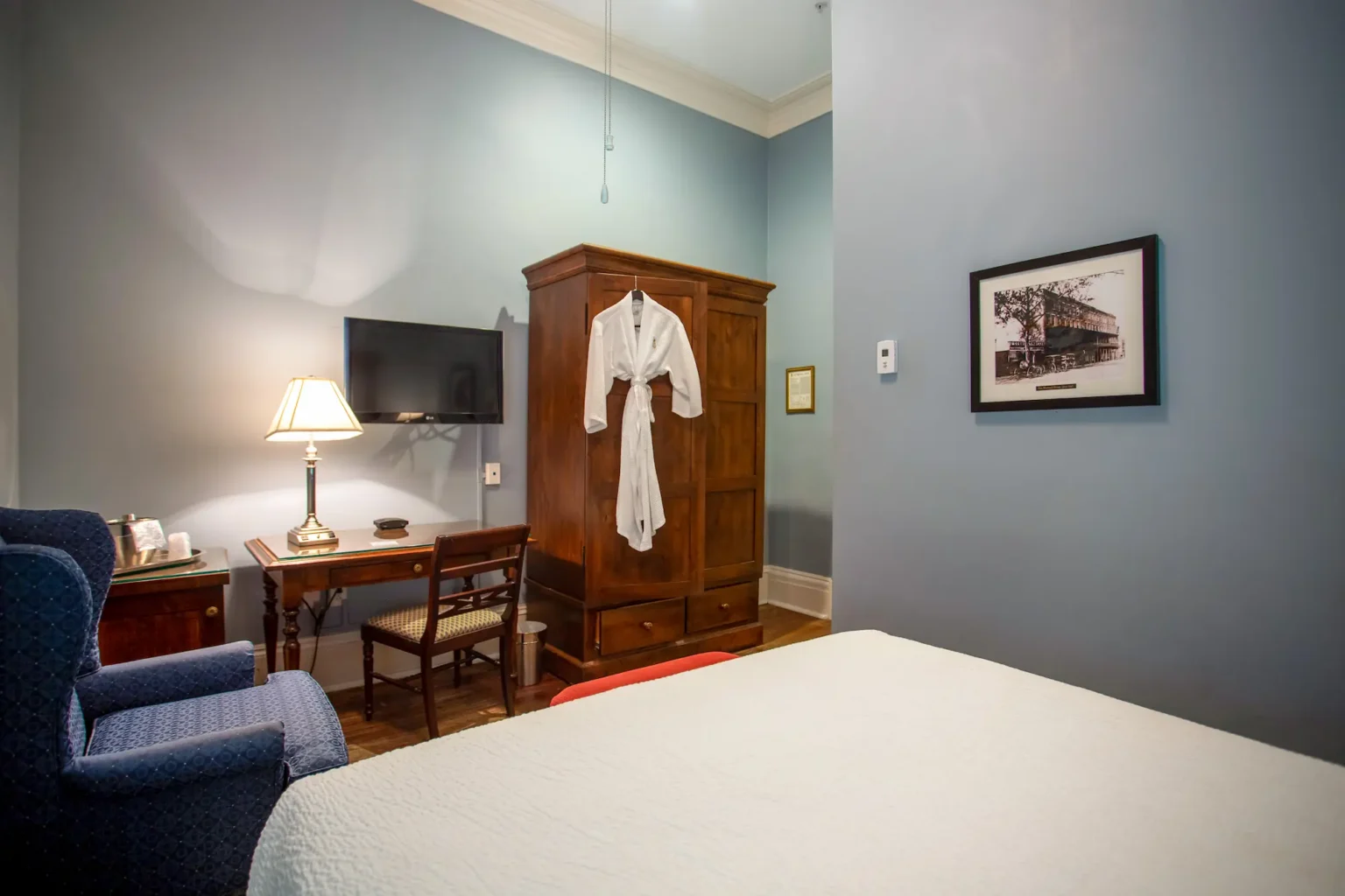 armoire, table, and bed in the petite queen room at the Marshall House hotel